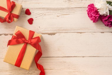 Kırmızı kurdele ve karanfilli Kraft hediye kutusu. Anneler gününde hediye verme konsepti. Sürpriz, düz yatak, üst manzara.