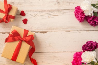 Kırmızı kurdele ve karanfilli Kraft hediye kutusu. Anneler gününde hediye verme konsepti. Sürpriz, düz yatak, üst manzara.