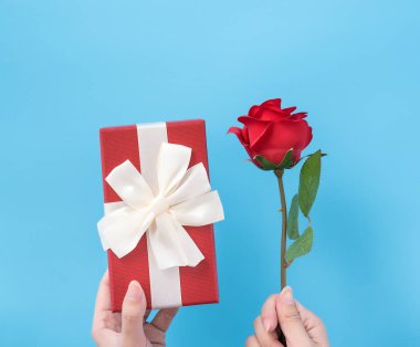 Genç bir kadın, bayram konsepti olan mavi arkaplanlı bir hediye veriyor ve festival için sürpriz, fotokopi alanı, üst görünüm için kutlama yapıyor.