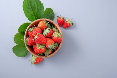 Bir kase güzel ve lezzetli çilek mavi arka planda izole edilmiş, yakın plan, üst görünüm, telif alanı.