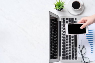 Bir kadın çevrimiçi ödeme ya da alışveriş yapıyor, ofis masasında kredi kartı ve cep telefonu taklidi yapıyor güzel moda mermer arka plan, üst görünüm, düz alan, telif alanı.