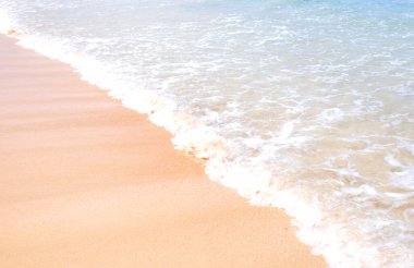 Güneşli mavi gökyüzü ile izole edilmiş yumuşak dalgaları olan harika, altın renkli kumlu plaj. Tropikal sakin turizm fikri, kopyala alanı, kapat