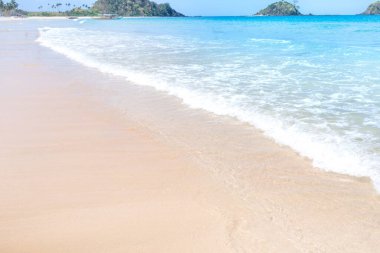 Güneşli mavi gökyüzü ile izole edilmiş yumuşak dalgaları olan harika, altın renkli kumlu plaj. Tropikal sakin turizm fikri, kopyala alanı, kapat