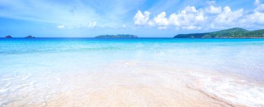 Güneşli mavi gökyüzü ile izole edilmiş yumuşak dalgaları olan harika, altın renkli kumlu plaj. Tropikal sakin turizm fikri, kopyala alanı, kapat