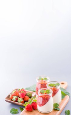 Havadar mavi arka plan, kopya alanı, yakın izole nane ve doğranmış sarkokus tepesi ile delikoz ve besleyici çift renkli (renkli) çilek tatlılar