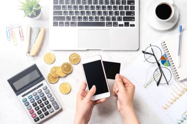 Bir kadın, modern bir mermer ofis masasına izole edilmiş kart ve akıllı telefonuyla çevrimiçi ödeme yapıyor. Model yapın, üst görünüm, fotokopi alanı, düz alan, yaşam tarzı, kapatın.