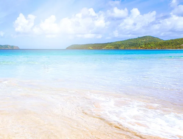 Güneşli mavi gökyüzü ile izole edilmiş yumuşak dalgaları olan harika, altın renkli kumlu plaj. Tropikal sakin turizm fikri, kopyala alanı, kapat
