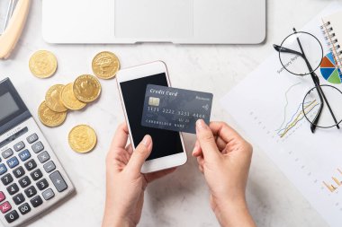 Modern bir mermer ofis masasına izole edilmiş bir telefon ve kartla online ödeme yapan bir kadın konsepti, üst görünüm, fotokopi alanı, düz yatak, yaşam tarzı, kapatın.