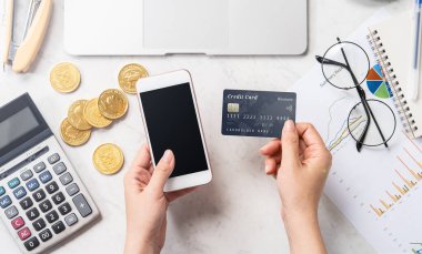 Modern bir mermer ofis masasına izole edilmiş bir telefon ve kartla online ödeme yapan bir kadın konsepti, üst görünüm, fotokopi alanı, düz yatak, yaşam tarzı, kapatın.