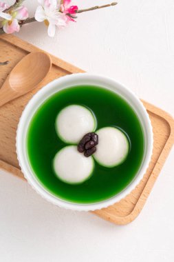 Matcha büyük tangyuan 'ın (tang yuan) beyaz masa arkasında tatlı kibrit çorbası ve kırmızı fasulye ezmesi ile festival yemeği için beyaz masa arkasında.