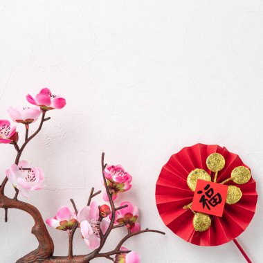 Top view of Chinese lunar new year background copy space design concept with pink plum blossom and festive decoration, the word inside picture means blessing.