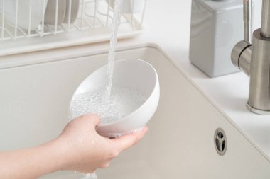 Kadın ev hanımı bulaşıkları yıkama süngeri ve bulaşık makinesiyle yıkıyor..