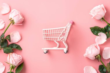 Sevgililer Günü alışveriş tasarımı konsepti pembe gül çiçeği ve el arabası arka planda.
