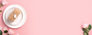 Sevgililer Günü hediyesinin ve yemek tasarımı konseptinin en üst görüntüsü pembe masa arkaplanlı pembe gül çiçeğiyle