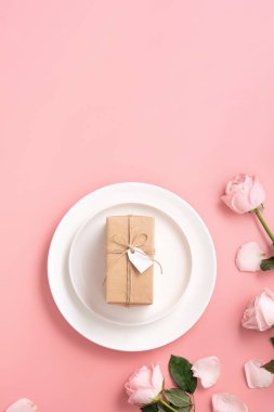 Sevgililer Günü hediyesinin ve yemek tasarımı konseptinin en üst görüntüsü pembe masa arkaplanlı pembe gül çiçeğiyle