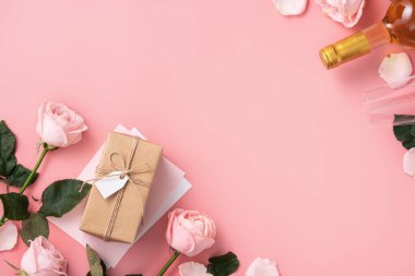 Sevgililer Günü hediyesinin en üst görüntüsü şarap ve pembe arkaplan tasarımı üzerine pembe gül buketi.