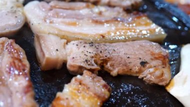 Kore restoranında tavada kızartılmış siyah domuz eti, demir tabakta taze Kore mutfağı ve marul.