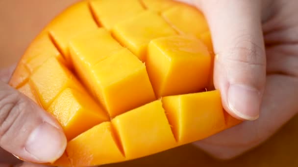 女性は新鮮なマンゴーの果物を切断し 食べるための家庭のキッチンでダイスされたパルプのジューシーな側面を示しています — ストック動画