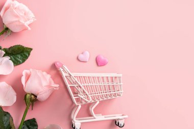 Sevgililer Günü alışveriş tasarımı konsepti pembe gül çiçeği ve el arabası arka planda.