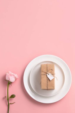 Sevgililer Günü hediyesinin ve yemek tasarımı konseptinin en üst görüntüsü pembe masa arkaplanlı pembe gül çiçeğiyle