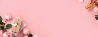 Sevgililer Günü hediyesinin en üst görüntüsü şarap ve pembe arkaplan tasarımı üzerine pembe gül buketi.