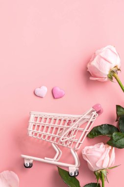 Sevgililer Günü alışveriş tasarımı konsepti pembe gül çiçeği ve el arabası arka planda.