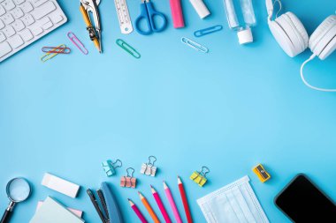 Çevrimiçi öğrenme ve okul tasarım konseptine geri dönüş. Mavi masa arkasında kulaklığı ve kırtasiyesi olan öğrenci tablosunun üst görünümü.