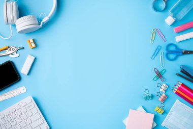 Çevrimiçi öğrenme ve okul tasarım konseptine geri dönüş. Mavi masa arkasında kulaklığı ve kırtasiyesi olan öğrenci tablosunun üst görünümü.