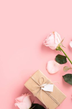 Sevgililer Günü tasarım konsepti pembe gül çiçeği ve paketlenmiş Kraft hediye kutusu ve pembe masa arkaplanı.