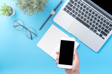 Bir kadın minimal mavi masa ile izole bir akıllı telefon tutuyor, online alışveriş ödeme kavramı, evde internet çalışması, e-ticaret, kopya alanı, düz yatıyordu, üst görünüm, alay
