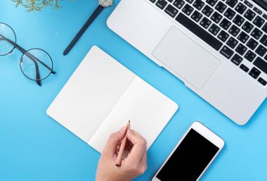 Bir öğrenci açık beyaz kitap veya muhasebe akıllı telefon ve aksesuarlar, kopya alanı, düz yatıyordu, üst görünüm, sahte ile evde minimal temiz mavi işyerinde izole yazmak