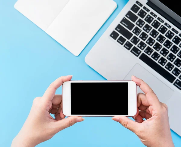 Bir kadın minimal mavi masa ile izole bir akıllı telefon tutuyor, online alışveriş ödeme kavramı, evde internet çalışması, e-ticaret, kopya alanı, düz yatıyordu, üst görünüm, alay