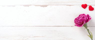 Anneler günü konsept fotoğrafçılığı - güzel karanfiller ve kalpler parlak ahşap bir masaya izole edilmiş beyaz bir kart, kopyalama alanı, düzlük, üst manzara, taklit