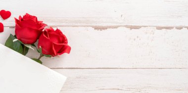 Selamlama konsepti - Parlak ahşap bir masaya izole edilmiş beyaz kart ile güzel güller ve kalpler, kopyalama alanı, düz yatış, üst manzara, taklit