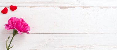 Anneler günü konsept fotoğrafçılığı - güzel karanfiller ve kalpler parlak ahşap bir masaya izole edilmiş beyaz bir kart, kopyalama alanı, düzlük, üst manzara, taklit