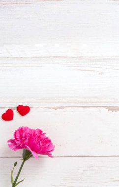 Anneler günü konsept fotoğrafçılığı - güzel karanfiller ve kalpler parlak ahşap bir masaya izole edilmiş beyaz bir kart, kopyalama alanı, düzlük, üst manzara, taklit