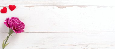 Anneler günü konsept fotoğrafçılığı - güzel karanfiller ve kalpler parlak ahşap bir masaya izole edilmiş beyaz bir kart, kopyalama alanı, düzlük, üst manzara, taklit