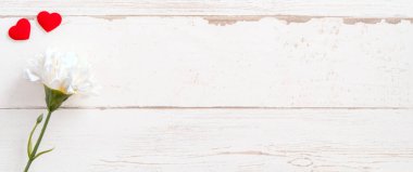 Anneler günü konsept fotoğrafçılığı - güzel karanfiller ve kalpler parlak ahşap bir masaya izole edilmiş beyaz bir kart, kopyalama alanı, düzlük, üst manzara, taklit
