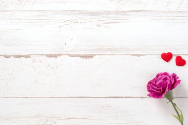 Anneler günü konsept fotoğrafçılığı - güzel karanfiller ve kalpler parlak ahşap bir masaya izole edilmiş beyaz bir kart, kopyalama alanı, düzlük, üst manzara, taklit