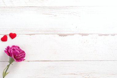 Anneler günü konsept fotoğrafçılığı - güzel karanfiller ve kalpler parlak ahşap bir masaya izole edilmiş beyaz bir kart, kopyalama alanı, düzlük, üst manzara, taklit