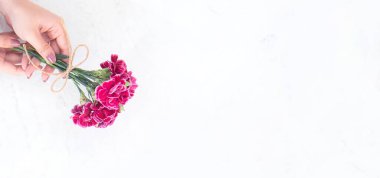 Anneler günü konsept fotoğrafçılığı - Güzel karanfiller halat yayı ile bağlanmış, modern, aydınlık masaya izole edilmiş, kopyalama alanı, düzlük, üst manzara