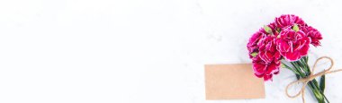 Anneler günü konsept fotoğrafçılığı - güzel karanfiller kraft yazılı kartla bağlanmış parlak modern masa, kopyalama alanı, düz yer, üst manzara, maket