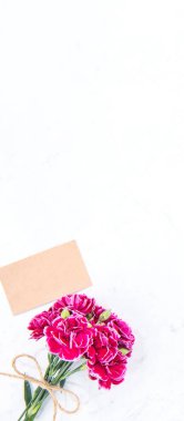 Anneler günü konsept fotoğrafçılığı - güzel karanfiller kraft yazılı kartla bağlanmış parlak modern masa, kopyalama alanı, düz yer, üst manzara, maket