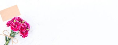 Anneler günü konsept fotoğrafçılığı - güzel karanfiller kraft yazılı kartla bağlanmış parlak modern masa, kopyalama alanı, düz yer, üst manzara, maket