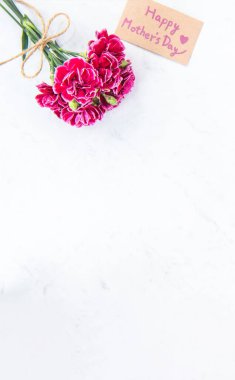 Anneler günü konsept fotoğrafçılığı - güzel karanfiller kraft yazılı kartla bağlanmış parlak modern masa, kopyalama alanı, düz yer, üst manzara, maket