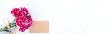 Anneler günü konsept fotoğrafçılığı - güzel karanfiller kraft yazılı kartla bağlanmış parlak modern masa, kopyalama alanı, düz yer, üst manzara, maket