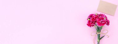 Anneler günü konsept fotoğrafçılığı - güzel karanfiller kraft yazılı kartla bağlanmış parlak modern masa, kopyalama alanı, düz yer, üst manzara, maket