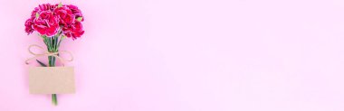 Anneler günü konsept fotoğrafçılığı - güzel karanfiller kraft yazılı kartla bağlanmış parlak modern masa, kopyalama alanı, düz yer, üst manzara, maket
