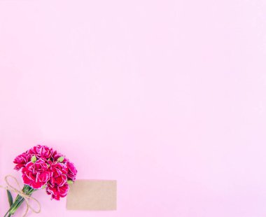 Anneler günü konsept fotoğrafçılığı - güzel karanfiller kraft yazılı kartla bağlanmış parlak modern masa, kopyalama alanı, düz yer, üst manzara, maket