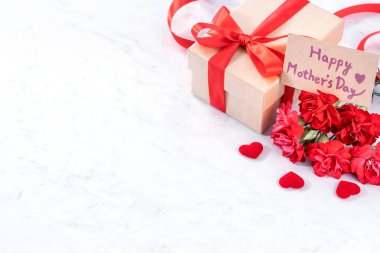 Mayıs anneler gün kavramı el yapımı giftbox fikir Fotoğrafçılık dilek-modern mermer masada izole kırmızı şerit yay kutusu ile güzel çiçeklenme karanfil, yakın çekim, kopya alanı, alay
